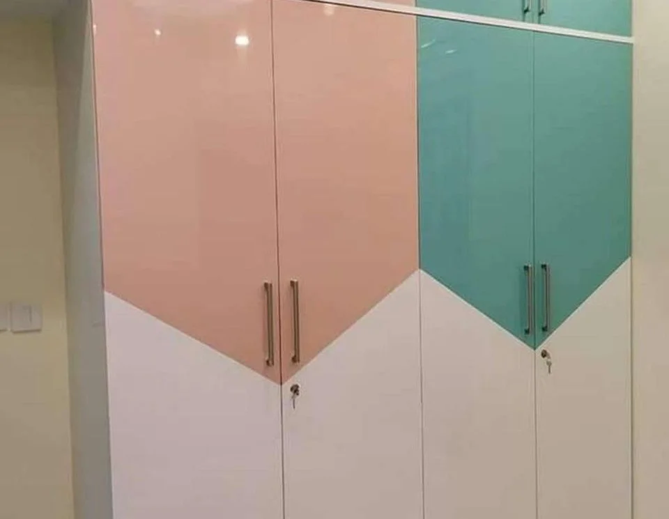 Modern color-blocked wardrobe in pink, teal, and white with metal handles.