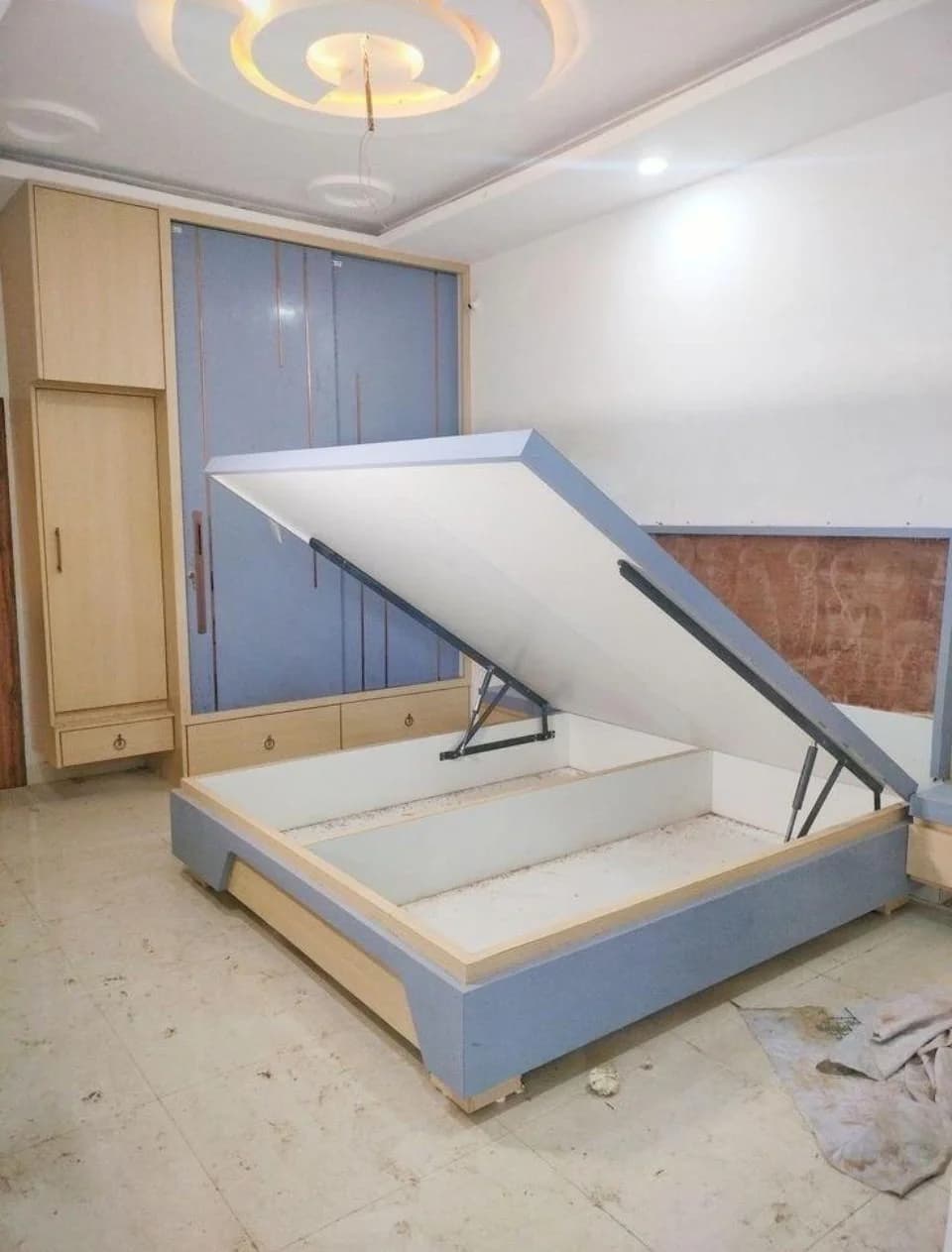 Open storage bed frame with light blue wardrobe, showing storage compartment.
